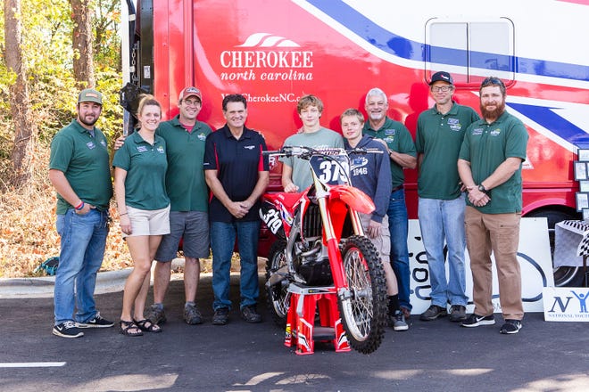 Black Mountain Home resident Johnny, center, receives a dirt bike from Honda, which was donated through Makson, Inc. owner David Eller, left of center.