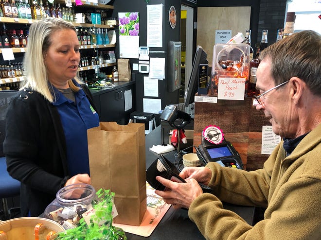Kelly Brockwell, left, store manager of the Arden ABC store, rings up customer Ronnie Waldrup on Wednesday, March 18. The store, like others in the nine-store Asheville ABC system, has been seeing near-record sales in the wake of the coronavirus pandemic.