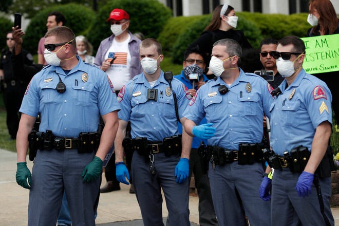 Capitol police watch as people with ReopenNC demonstrate in Raleigh, N.C., to press Gov. Roy Cooper to allow businesses to reopen during the COVID-19 outbreak Tuesday, April 21, 2020. (AP Photo/Gerry Broome)