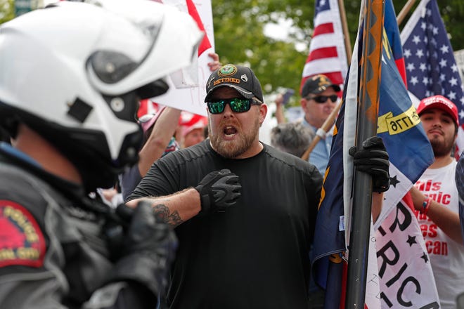A protester argues with police as people with ReopenNC gather in Raleigh, N.C., to press Gov. Roy Cooper to allow businesses to reopen during the COVID-19 outbreak Tuesday, April 21, 2020. (AP Photo/Gerry Broome)