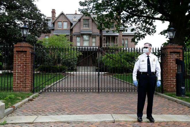 Capitol Chief of Police R.E. Hawley guards the entrance to the Governor's mansion as people with ReopenNC demonstrate in Raleigh, N.C., to press Gov. Roy Cooper to allow businesses to reopen during the COVID-19 outbreak Tuesday, April 21, 2020. (AP Photo/Gerry Broome)