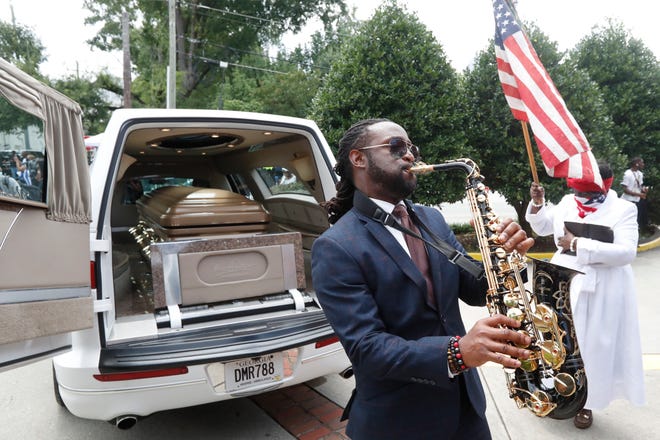 A musician plays music near the hearse carying the casket of Rayshard Brooks.